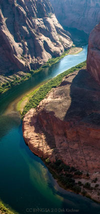 Red sandstone walls tower above a canoe on the Green River.